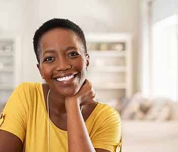 Woman in yellow shirt smiling at home