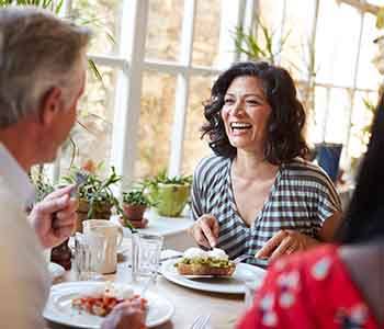 Woman smiling while eating lunch at restaurant with friends