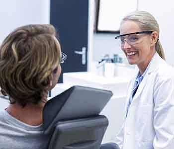 Smiling dentist talking to patient in exam room