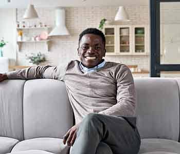 Man smiling while relaxing on couch at home