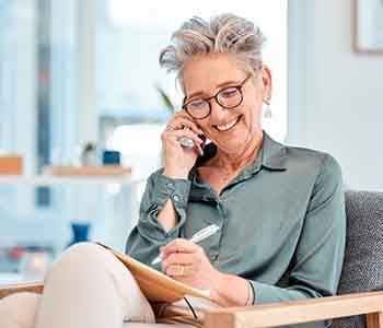 Smiling woman taking notes while talking on phone