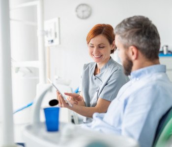 Dentist reviewing information on tablet with patient