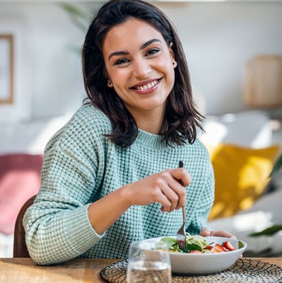Smiling woman sitting at table, eating a healthy meal
