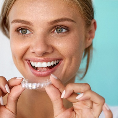 Smiling woman holding teeth whitening tray